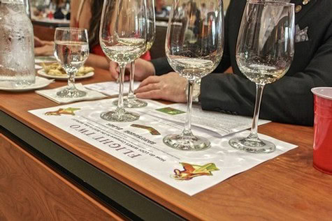 Wine tasting setup with four glasses of white wine on a wooden table at a Lodi wine event.