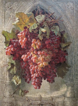 Close-up of a ripe red and pink winegrape cluster with green leaves on a textured background.