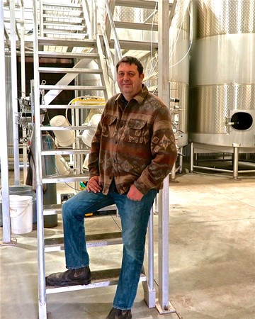Man standing on winery stairs at Lodi Winegrape Commission, California, showcasing wine production equipment.