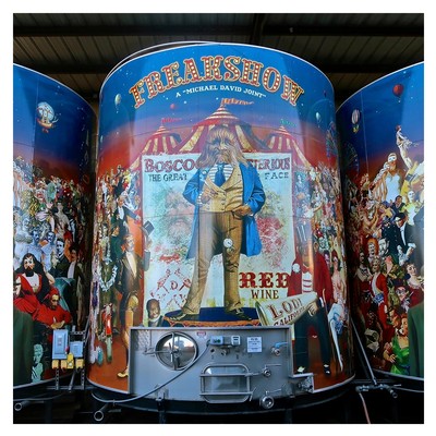 Colorful circus-themed display with a central figure in a blue coat and top hat, surrounded by vibrant illustrations and text.