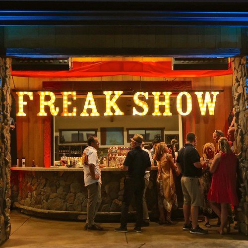People gathered at the Freak Show event at Lodi Winegrape Commission with bright marquee sign and lively atmosphere.
