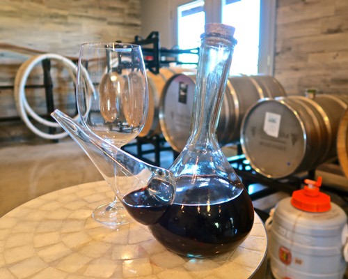 Glassware with red wine and wine barrels in the background at Lodi Winegrape Commission.