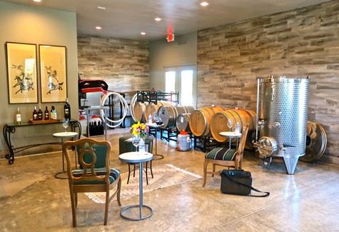 Wine tasting room with barrels, chairs, and wine bottles at Lodi Winegrape Commission.