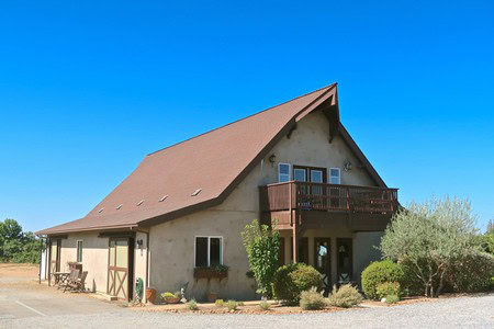 Charming winery building with a steep roof, balcony, and surrounding greenery in Lodi, California.