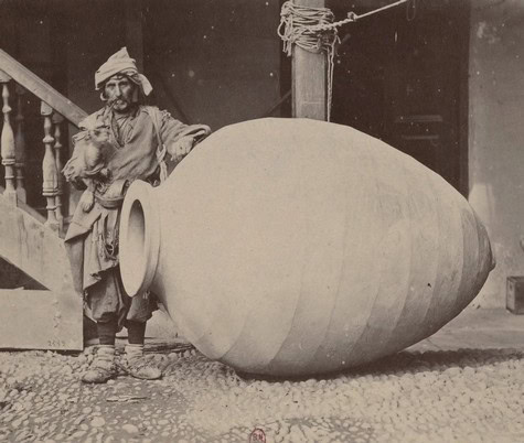 Vintage photo of a man with a large ceramic vessel, likely from the 19th or early 20th century.