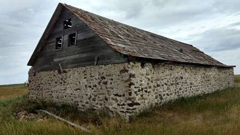 Old wooden barn with stone foundation in Lodi wine region, California, under cloudy sky.