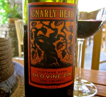 Bottle of Gnarly Head Old Vine Zinfandel 2008 wine with glass of red wine on wooden table.