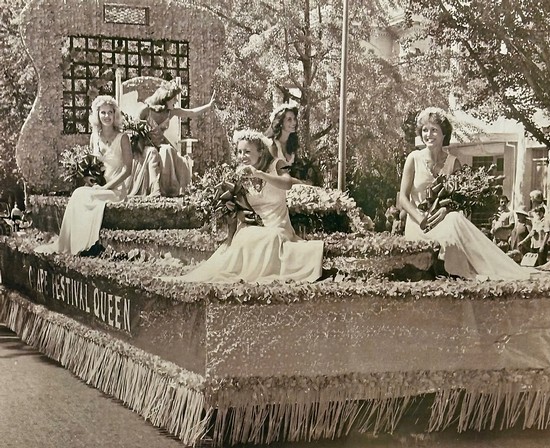 Vintage parade float with women in elegant dresses, flowers, and parasols, celebrating Lodi wine culture.