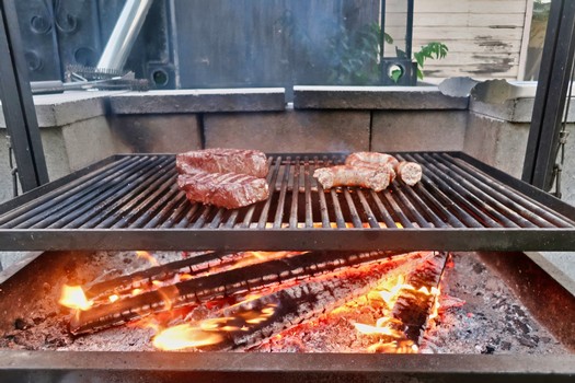 Barbecue grill with steaks cooking over open flame, Lodi Winegrape Commission event.