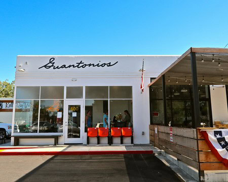 Guantonios wine tasting room in Lodi with outdoor seating and clear glass windows under a bright blue sky.