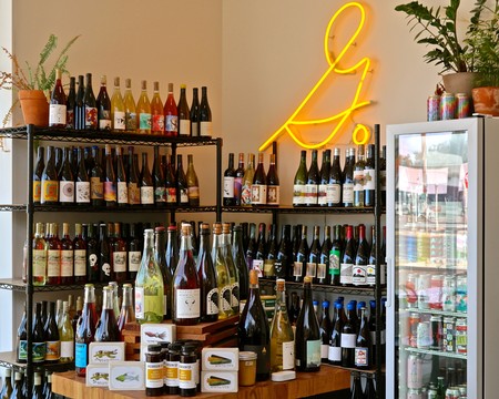Wine bottles and jars displayed at Lodi Winegrape Commission with neon bird sign in background.