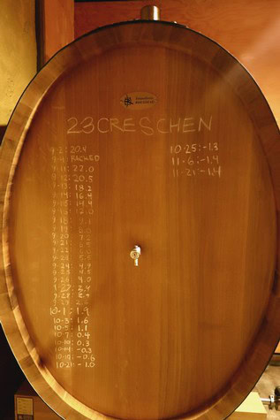 Wooden wine barrel with measurement markings for wine aging and fermentation process.