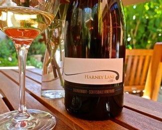 Close-up of a wine bottle from Lodi Winegrape Commission on a wooden table with a glass of rosé wine.
