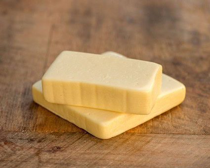 Close-up of two slices of cheese on a wooden surface, highlighting their texture and color.