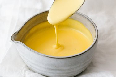 Creamy yellow sauce being poured into a bowl, representing Lodi wine and culinary traditions.