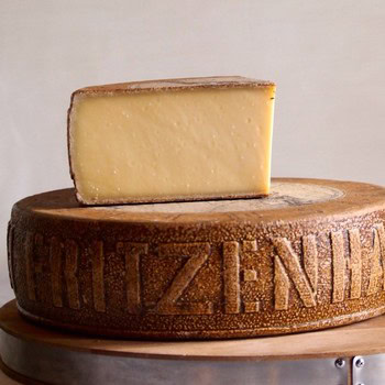 Close-up of a cheese wheel with the Lodi Winegrape Commission logo engraved on the side and a cheese wedge on top.