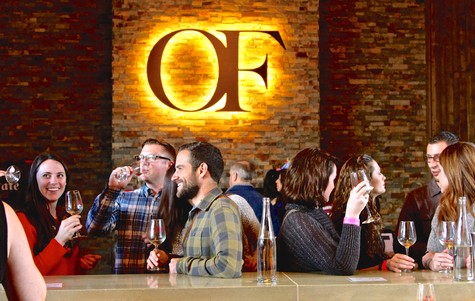 Group of people enjoying wine tasting at Lodi Winegrape Commission event with wine glasses and a brick wall background.