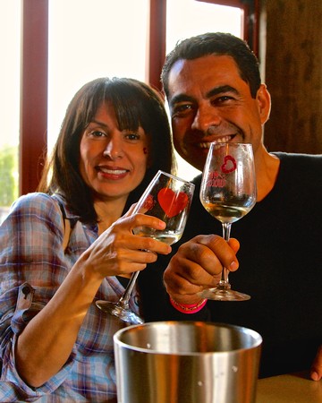 Happy couple enjoying wine at Lodi Winegrape Commission event, smiling and clinking glasses.