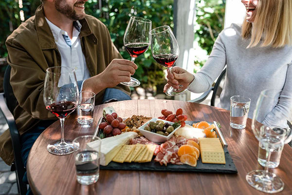 Couple enjoying wine tasting with cheese and grapes at Lodi Winegrape Commission event.