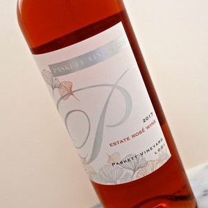 Close-up of a 2017 estate rosé wine bottle from Lodi Winegrape Commission with a white label and floral design.