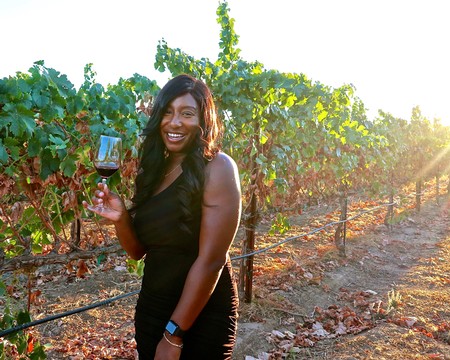 Woman enjoying wine tasting in a lush Lodi vineyard during sunset.