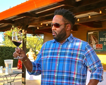 Man enjoying a glass of red wine outdoors at a wine tasting event in Lodi, California.
