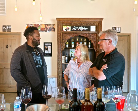Three people enjoying a wine tasting at Lodi Winegrape Commission with wine glasses and bottles on the table.