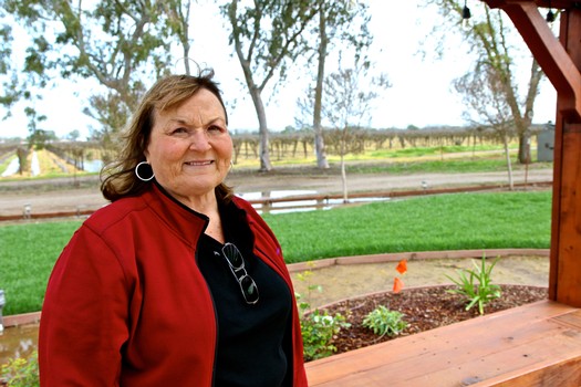Portrait of a woman in a red jacket at a vineyard, representing Lodi Winegrape Commission, California wine region.