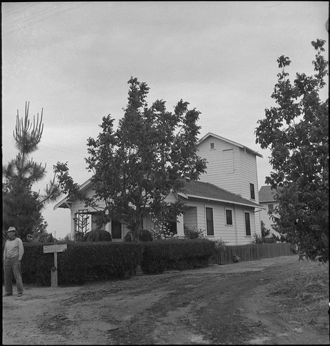 Historic building of the Lodi Winegrape Commission surrounded by trees and bushes in a rural setting.
