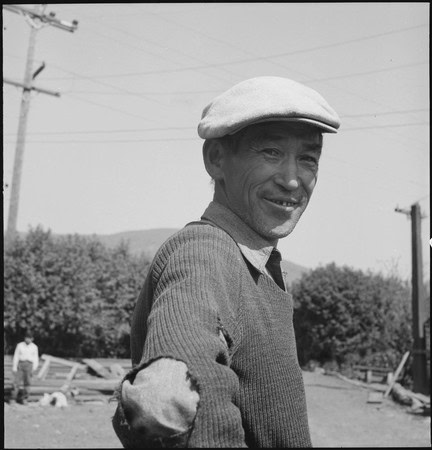 Black and white photo of a smiling vineyard worker wearing a cap in Lodi, California.