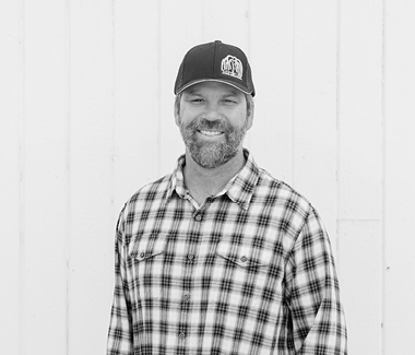 Smiling man in plaid shirt and baseball cap at Lodi Winegrape Commission event.