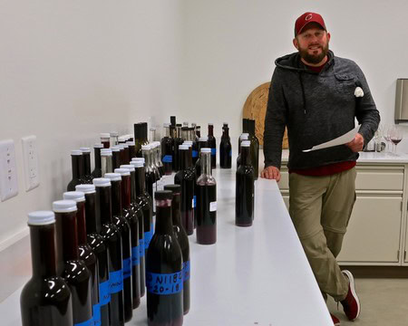 Man with wine bottles at Lodi Winegrape Commission tasting event, showcasing local wine varieties.