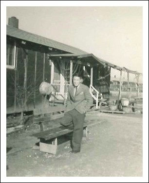 Historical black and white photo of a man sitting on a bench at a vineyard in Lodi, California.