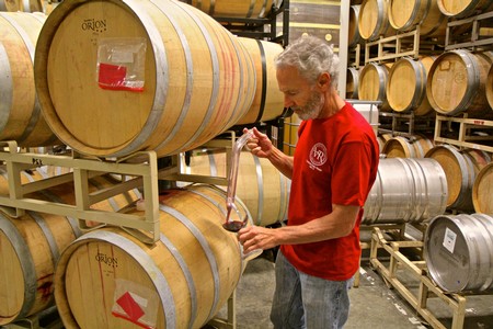 Winemaker inspecting wine barrels at Lodi Winegrape Commission facility.