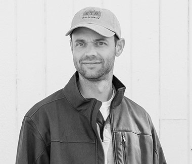 Man wearing a cap and jacket standing outdoors, Lodi Winegrape Commission.