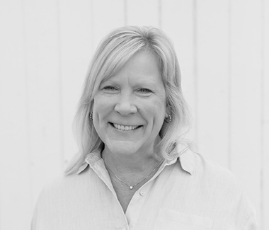 Smiling woman with blonde hair in front of a white background, professional portrait.