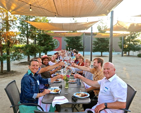 Group of people enjoying a wine tasting event outdoors under shade sails in Lodi, California.