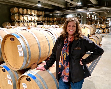 Woman smiling in winery surrounded by wine barrels at Lodi Winegrape Commission.