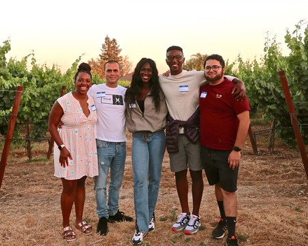 Group of diverse people smiling and standing in a vineyard during a community event in Lodi, California.