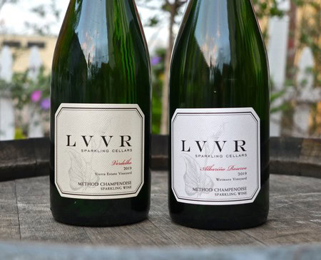 Two bottles of sparkling wine from Lodi Winegrape Commission, vintage 2019, Method Champenoise, on a wooden surface.