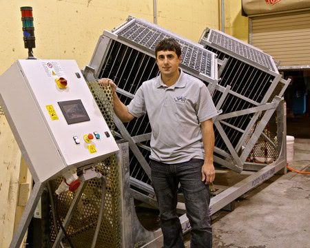 Man standing next to wine grape harvesting equipment at Lodi Winegrape Commission facility.
