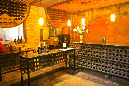 Interior of a wine tasting room with wine bottles, glasses, and decorative wine barrel elements.