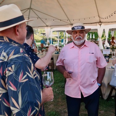 Men enjoying wine tasting at a Lodi Winegrape Commission event under a tent.