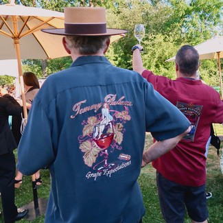 Person wearing a blue shirt with Lodi Winegrape Commission logo at outdoor wine event.