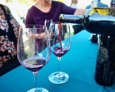 Pouring red wine into glasses at a wine tasting event by the Lodi Winegrape Commission.