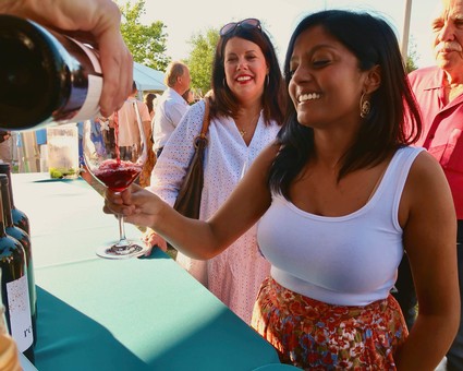 Woman enjoying wine tasting at Lodi Winegrape Commission event with friends.