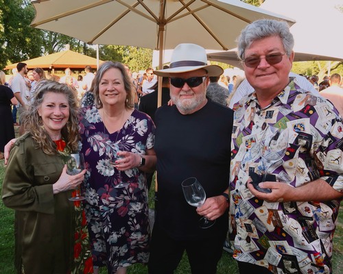 Group of people enjoying wine tasting at Lodi Winegrape Commission event outdoors.