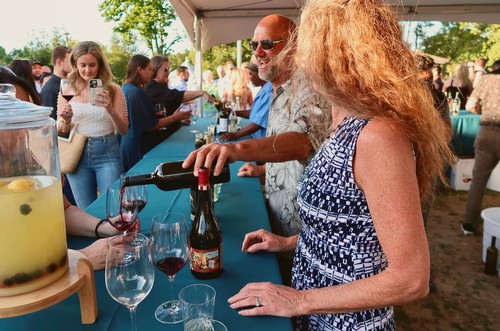 People enjoying wine tasting at an outdoor event hosted by the Lodi Winegrape Commission.
