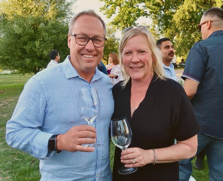 Smiling man and woman holding wine glasses at Lodi Winegrape Commission event outdoors.