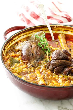 A hearty lamb and lentil stew served in a red pot with vegetables and herbs, perfect for a comforting meal.
